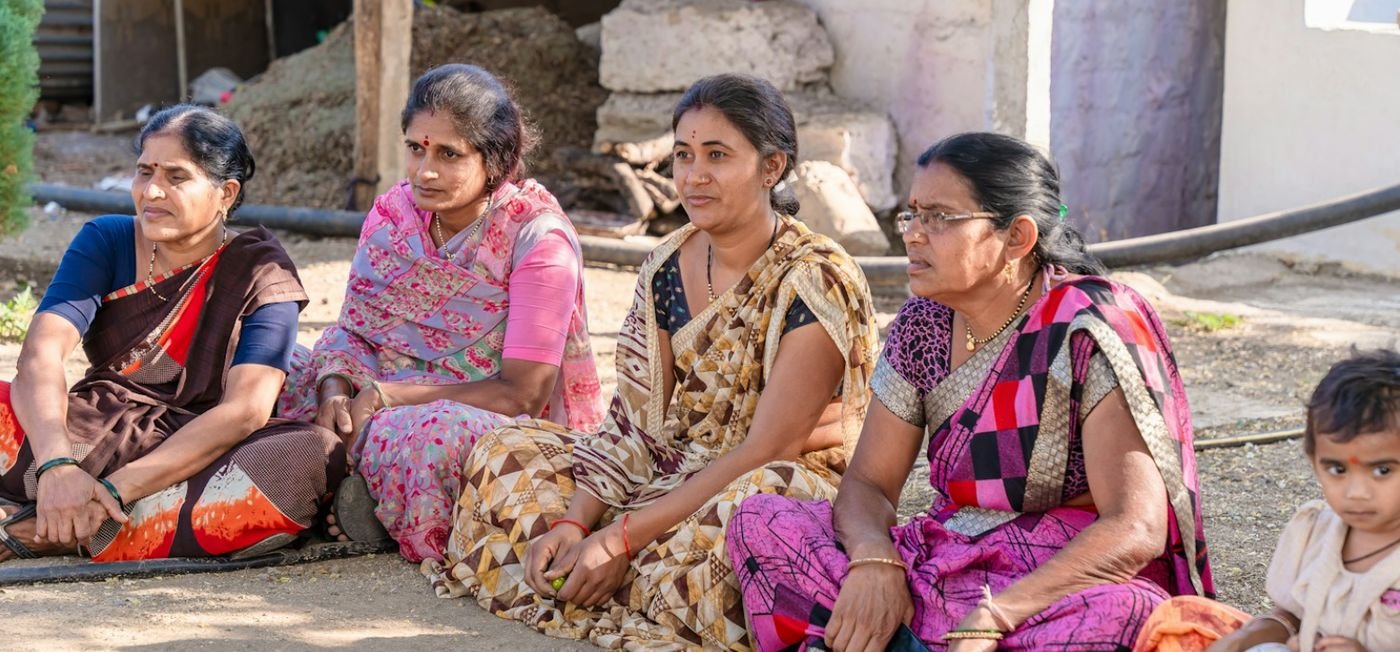Four women seated together outdoors in an Indian village, as at a self-help group meeting (representative image)